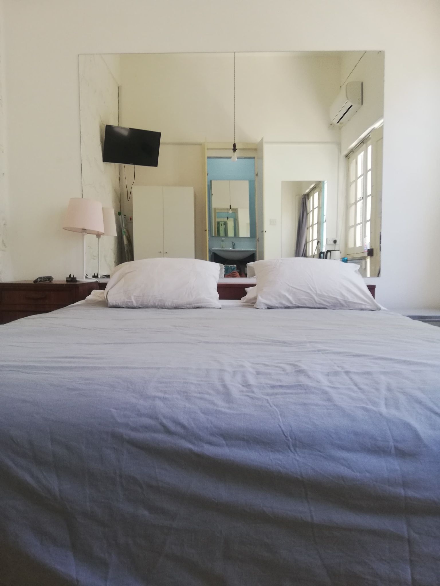 Bedroom with two pillows and big mirror on the wall